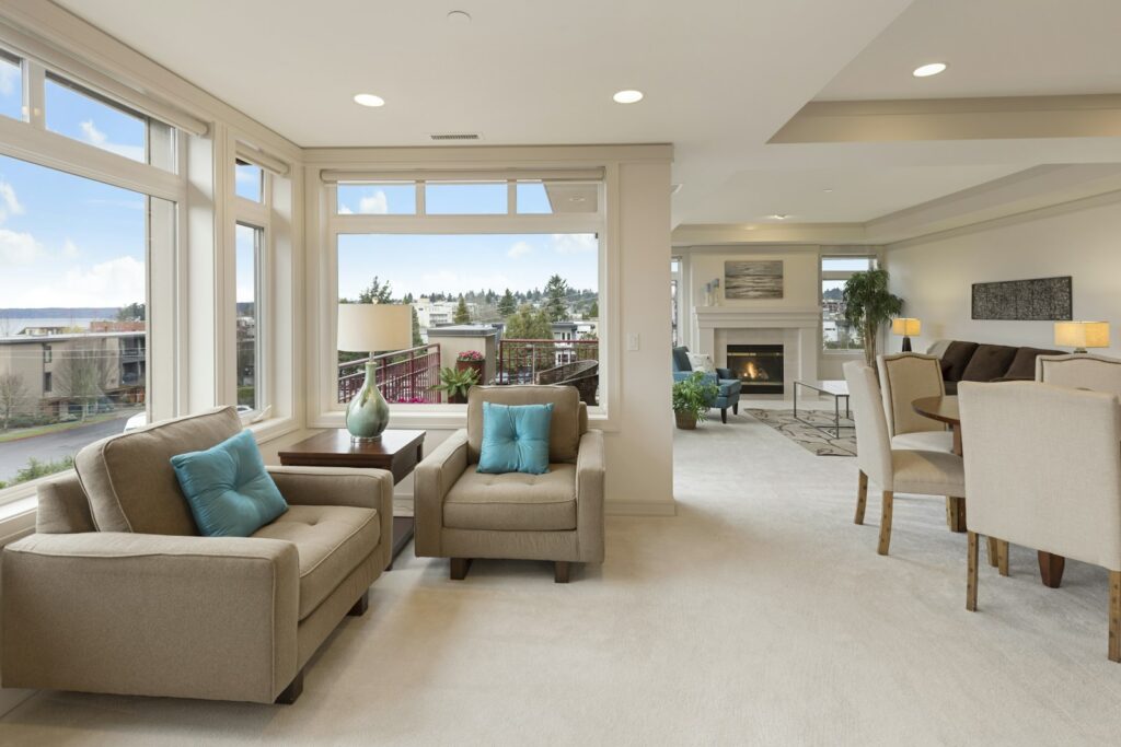 Staged living room with neutral furniture, accent pillows and open sightlines to the dining area