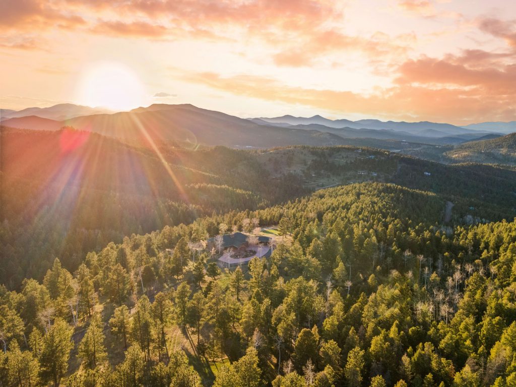 Sunrise over a private mountain retreat surrounded by wooded acreage in Conifer, Colorado, featuring breathtaking mountain views and a serene natural landscape.