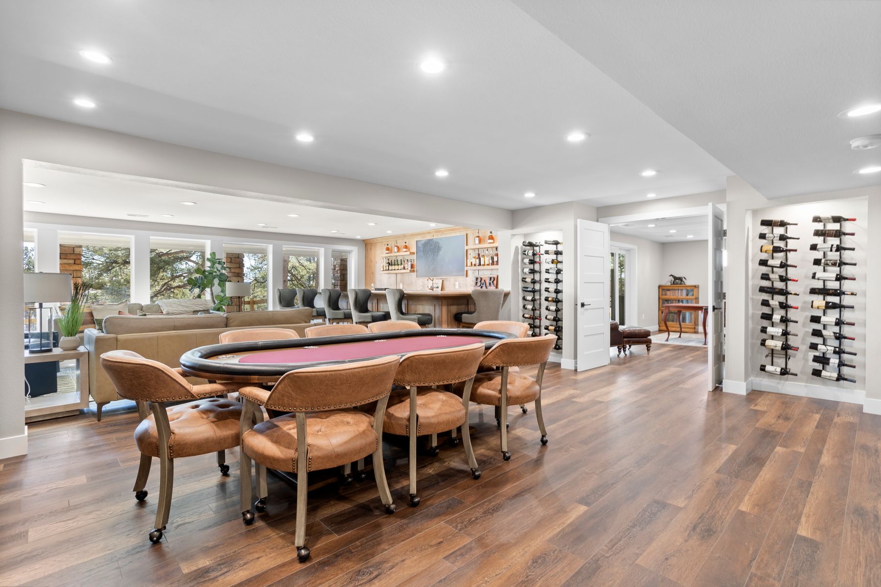Lower-level entertainment space at 8740 Hilltop Road featuring poker table, custom bar, and wine storage