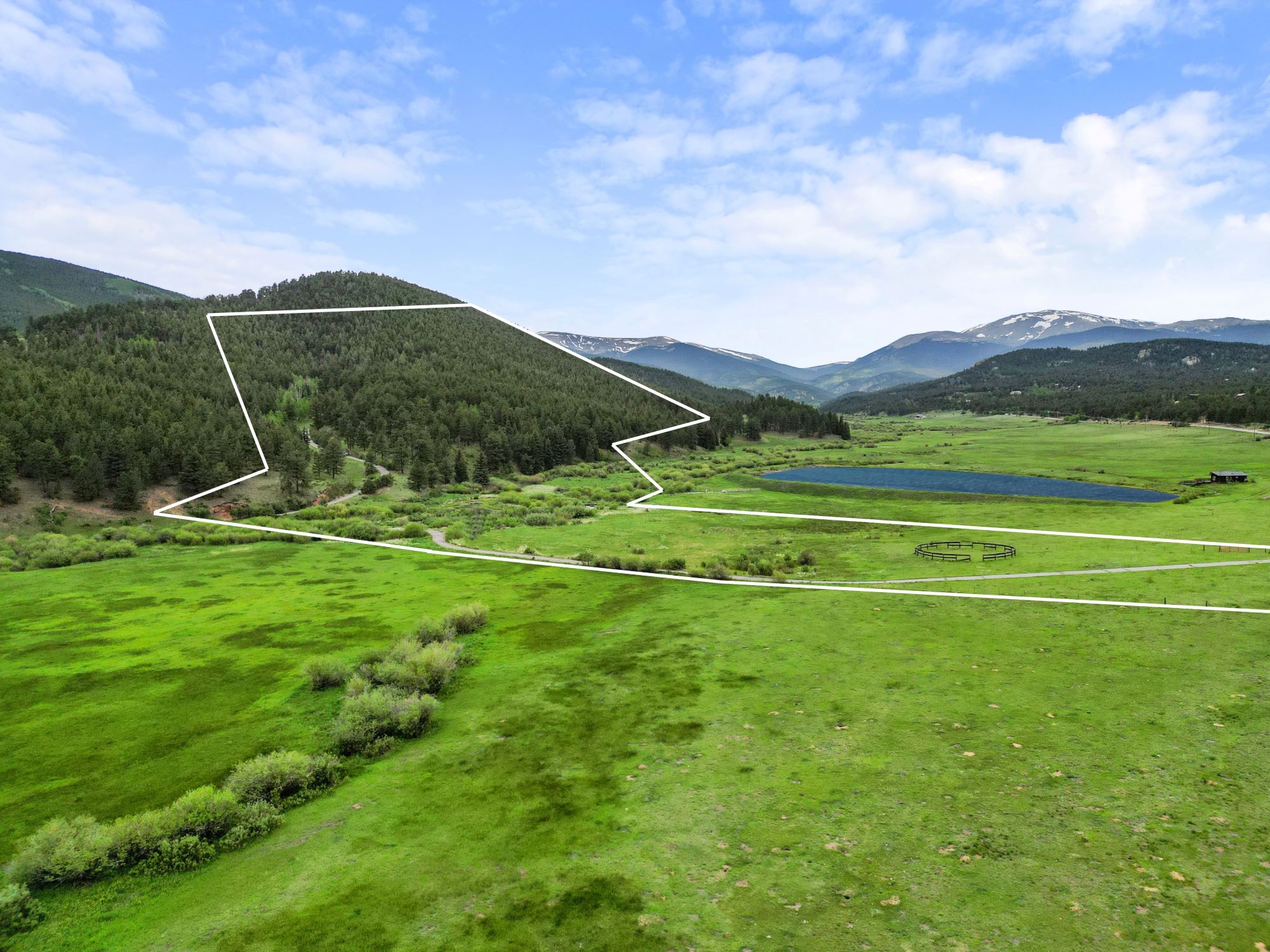 Mountain acreage in Bailey, Colorado with defined property lines, pine-covered hills, a private pond, and sweeping valley and mountain views.