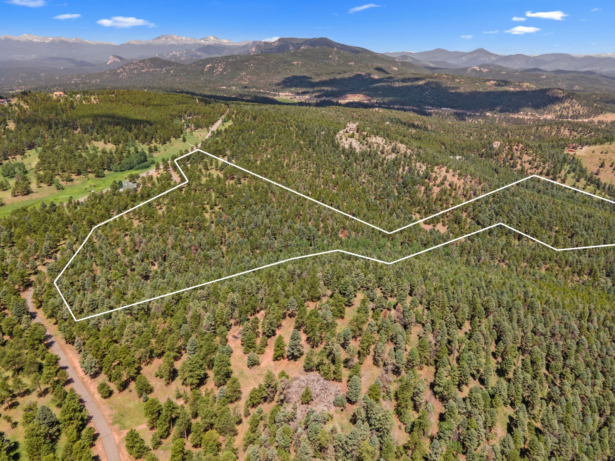 Beautifully forested land in Conifer, Colorado with clearly marked property lines and mountain views, ideal for development or recreation.