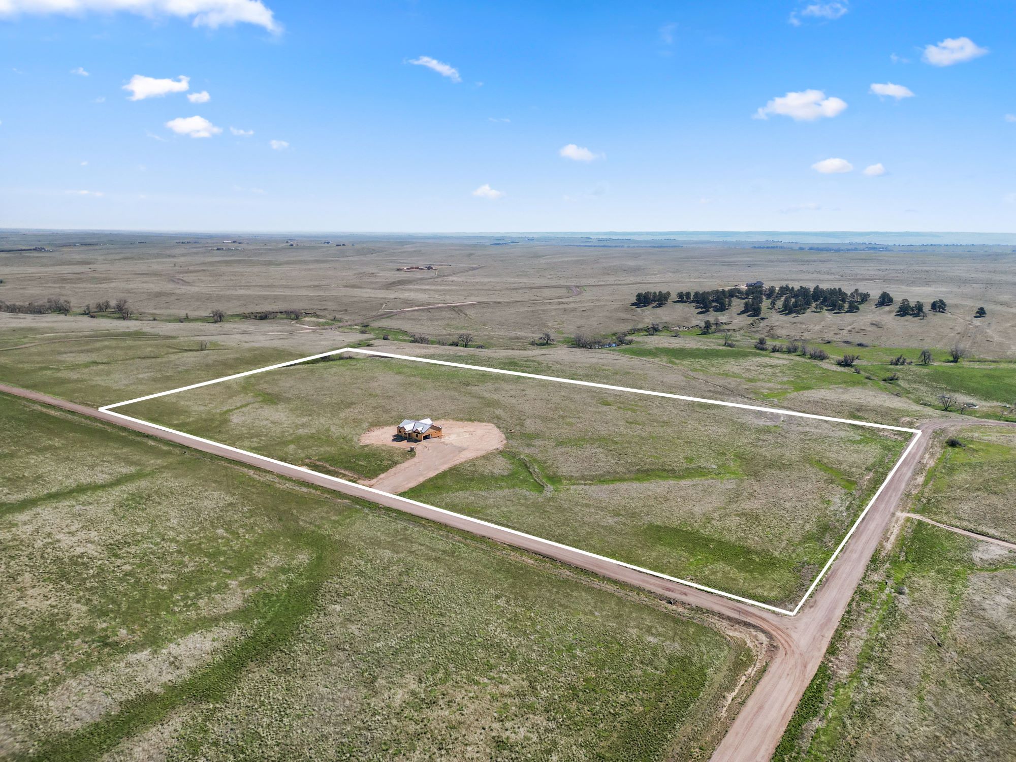 Expansive 35-acre parcel in Kiowa, Colorado with a small structure centered on open plains, outlined borders, and distant rural views under a blue sky.