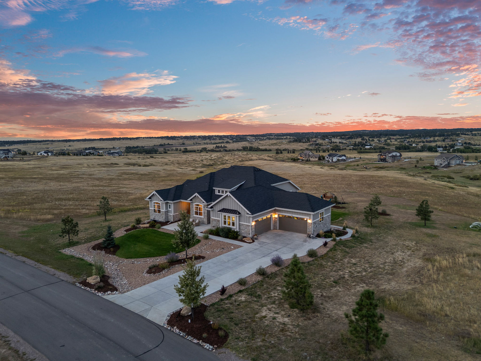 Aerial view of 9141 Red Primrose Street showing private 8-acre estate setting surrounded by open meadows and neighboring custom homes.