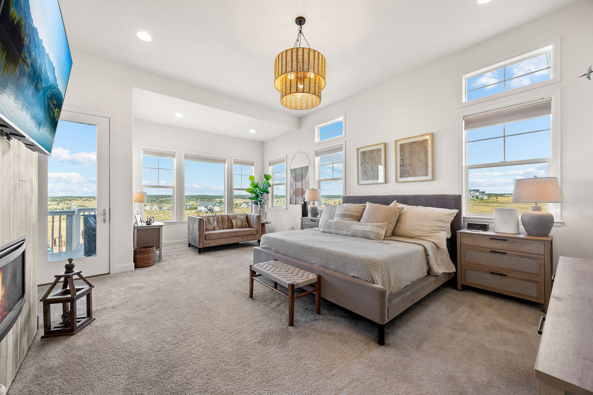 Primary bedroom with fireplace, large windows, sitting area, and views of rolling hills in Franktown, Colorado.