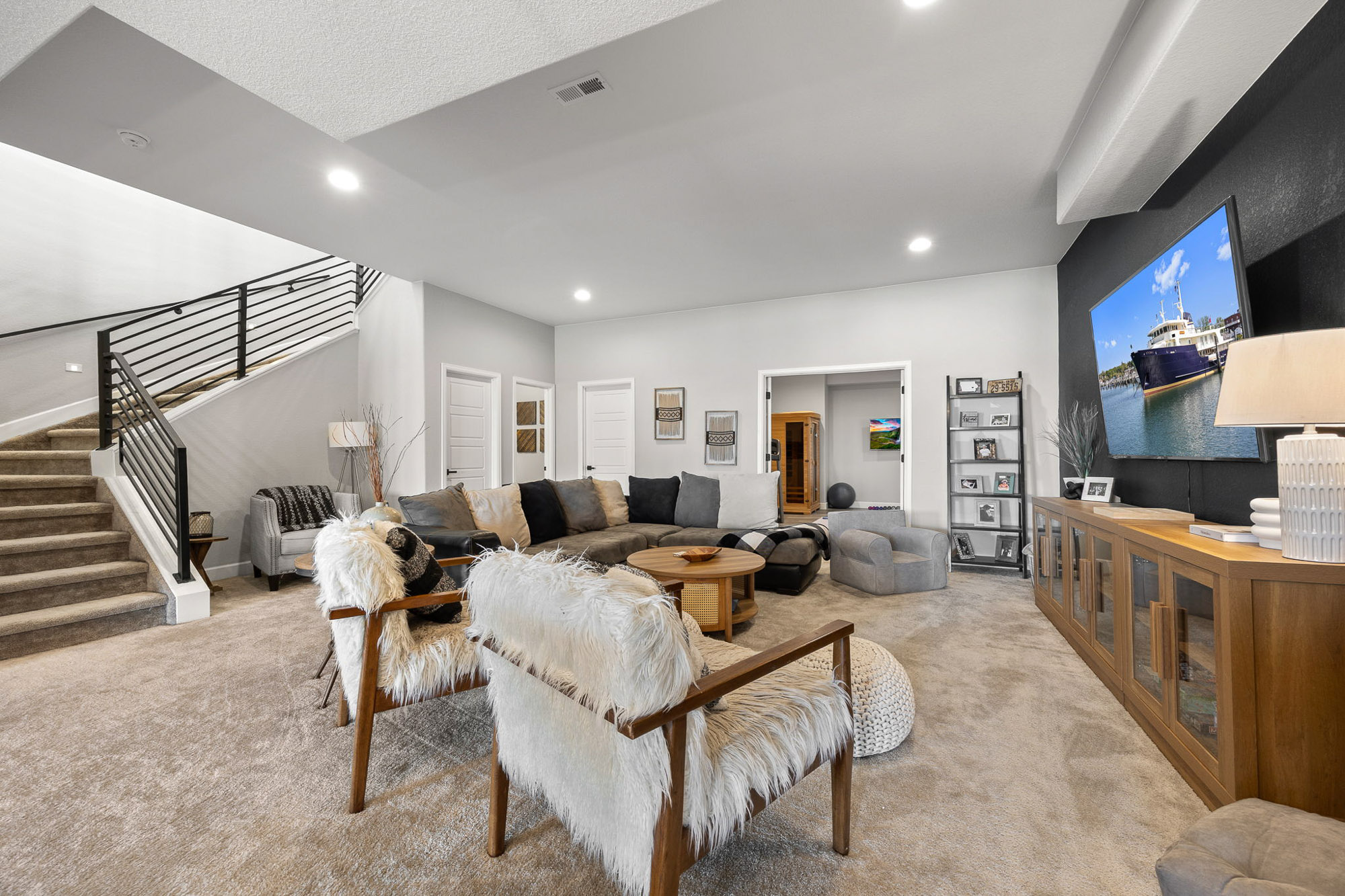 Finished lower level with family room, modern staircase, and media area for relaxation and entertaining.