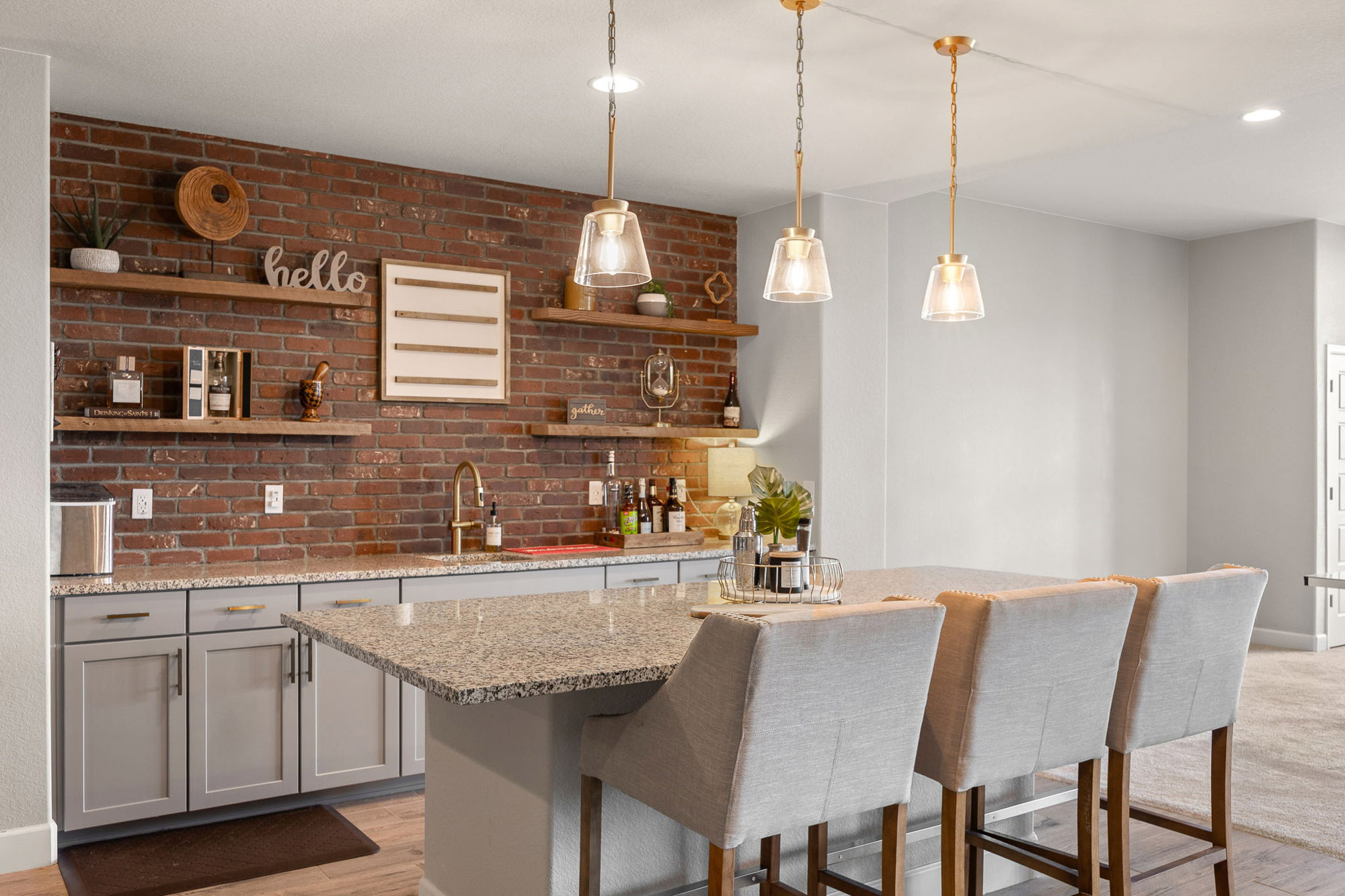 Wet bar with brick accent wall, pendant lights, granite counters, and open shelving in the lower level.