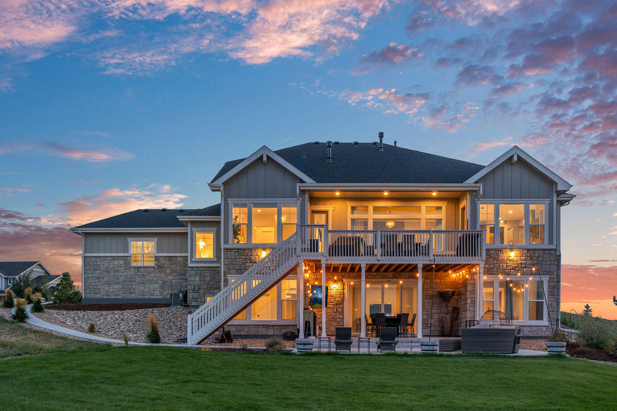 Rear exterior of 9141 Red Primrose Street at twilight with upper deck, covered patio, and manicured lawn.