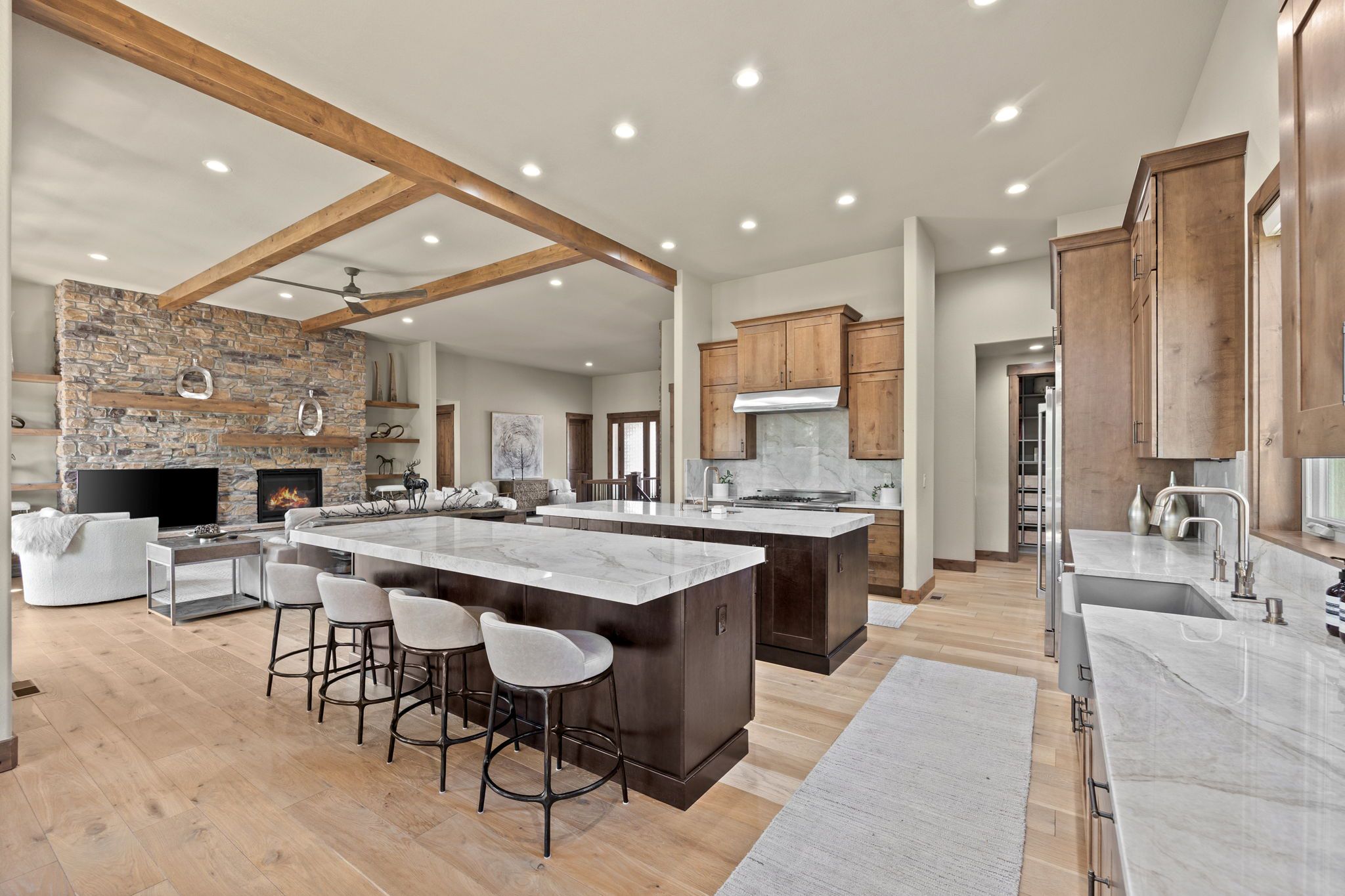 Gourmet kitchen at 5612 Ponderosa Drive with Taj Mahal quartzite island, open great room layout, wood beams, and stone fireplace.